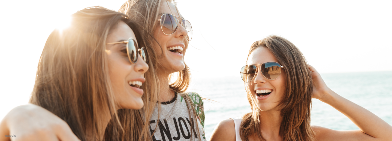 group of three women friends smiling and walking along the beach